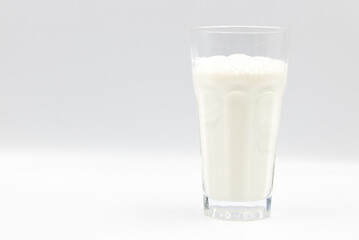 Milk in glass closeup on a white background.