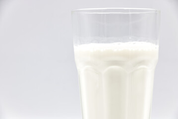 Milk in glass closeup on a white background.