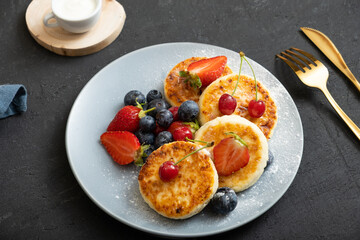 Roasted cheesecakes on a plate with powdered sugar and berries angle view