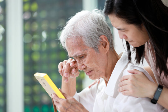 Unhappy old elderly grandmother crying tears looking at photograph of family with  sorrow,sad asian senior people holding photo frame of her deceased husband,a feeling of deep distress caused by loss