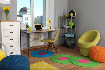 Comfortable workplace with modern laptop near window in child room. Interior design