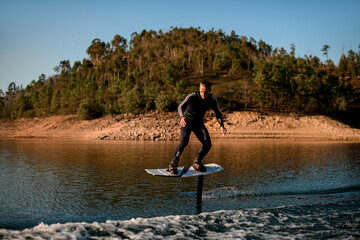 man masterfully rides on river water on a foil wakeboard on beautiful landscape background.