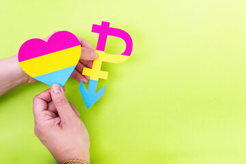 Two hands holding heart of pansexual flag colors, love has no gender. Pansexual symbol.