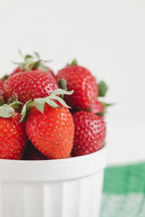 Fresh red strawberries close up in a white bowl. Healthy breakfast with berries.