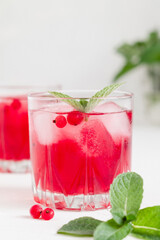 Cranberry cocktail with ice and mint on a white background.