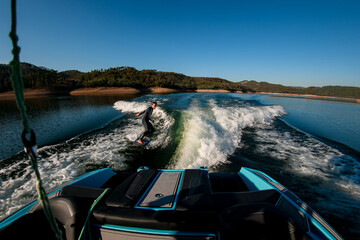 Great view from boat on man masterfully riding on a wave on a wakesurf board