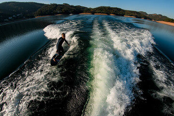 high angle view of young athletic man balancing on a wave on a wakesurf board
