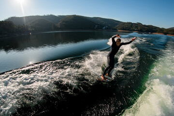beautiful view of sportive man skillfully balancing with wakesurf board on a wave