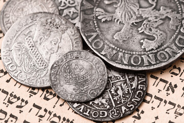 Pile of old silver coins on open Siddur page. Selective focus. Closeup.