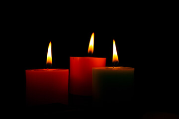 three burning candles on black background