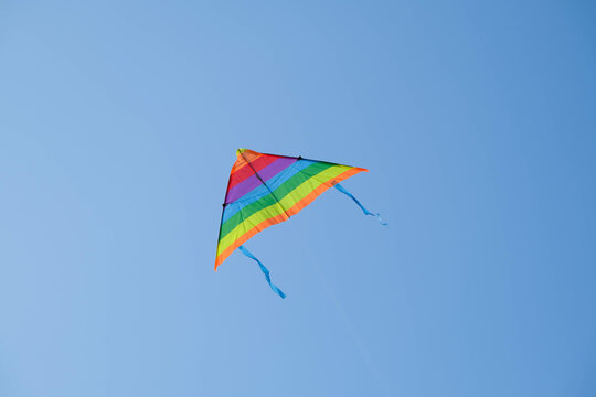 Colorful kite with flying tail in the blue sky on a hot summer day.