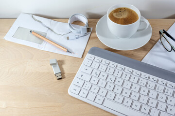 Computer keyboard, coffee, usb stick and papers on a wooden office desk for business at home, copy...