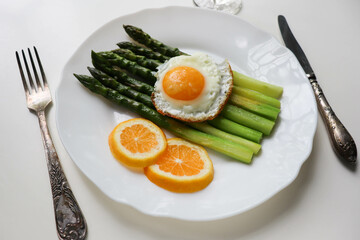 asparagus, lemon and scrambled eggs on a white dish. table setting