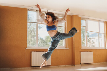 Young woman dancer make freedom jump while dancing in the hall