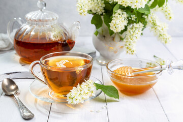 Useful spring tea with bird cherry in a transparent cup on a light background
