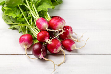 A bunch of red fresh radishes on a light wooden background. Copy space