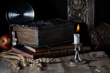 Burning candle on the background of old books on a wooden table