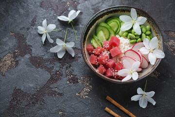 Bowl with ahi poke on a brown stone background with flowers, horizontal shot with space, high angle...