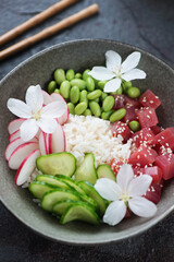 Obraz na płótnie Canvas Close-up of hawaiian tuna poke bowl with flowers, vertical shot, selective focus
