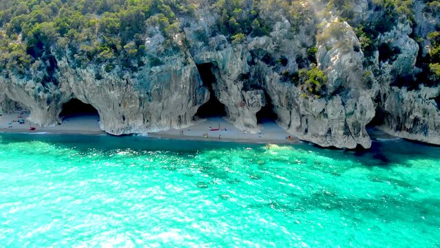 Golfo di Orosei Sardina, View from above, stunning aerial view of a beach full of beach umbrellas and people sunbathing and swimming on turquoise water. Cala Gonone, Sardinia, Italy, Cala Mariolu.
