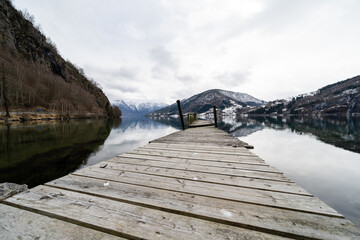 Norwegian fjord with clear water, where there is an old wooden footbridge at the boat dock