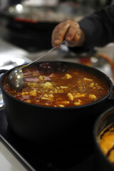 chef guisando una cazuela de legumbres con morcilla y verduras