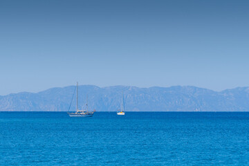 Fototapeta premium Tow sailing boats in ocean,in the background mountains.