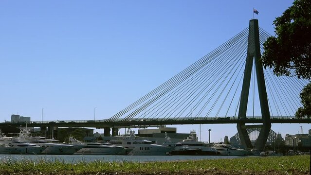 Sydney ANZAC Bridge, seeing boats driving under the bridge along the river and seeing cars traffic on the bridge in NSW Australia