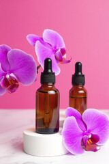 Fototapeta na wymiar Beauty collagen face oil in a glass dropper bottles on podium with orchid flowers. Trendy shoot of cosmetics packaging. Essential oil with natural ingredients.