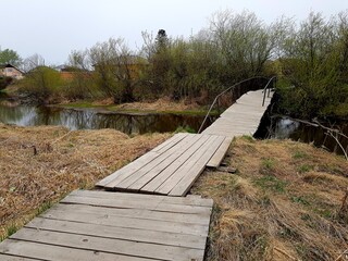 Fototapeta na wymiar Old wooden footbridge over a stream