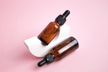 Beauty collagen face serum in a glass dropper bottle in Arch on pink background. Trendy shoot of cosmetics packaging. Essential oil with natural ingredients.