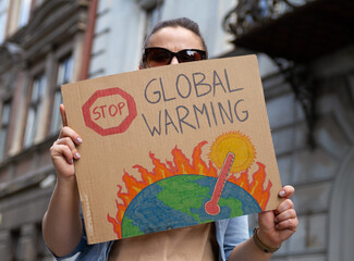 Protester holding sign with slogan Stop Global Warming. Woman with placard at protest rally...