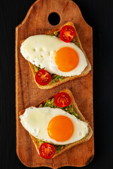 Homemade Healthy Egg, Avocado and Tomato Toast on a rustic wooden board, top view. Flat lay, overhead, from above. Close-up.