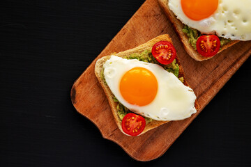 Homemade Healthy Egg, Avocado and Tomato Toast on a rustic wooden board, top view. Flat lay, overhead, from above. Space for text.