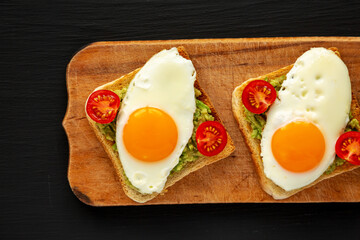 Homemade Healthy Egg, Avocado and Tomato Toast on a rustic wooden board, top view. Flat lay, overhead, from above.