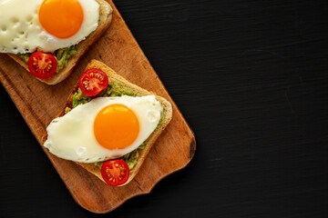 Homemade Healthy Egg, Avocado and Tomato Toast on a rustic wooden board, top view. Flat lay, overhead, from above. Copy space.