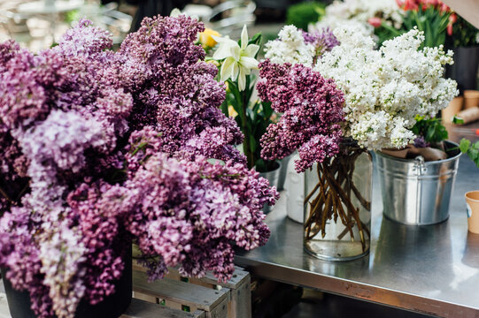 white and foil lilacs in vases for sale at a flower fair