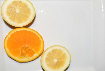 Lemon and orange slices on white plate.