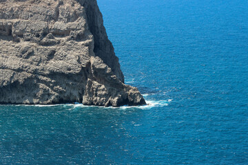 Steep rock face of a cliff coming out of deep blue Mediterranean sea water in Majorca Spain