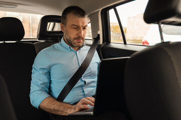 Businessman using laptop while going by car