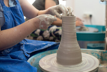 Master works on potter's wheel, doing blank. Hands of person sculpt vase from white clay. Workshop for manufacturing potter's products. Concept of creative, skill and handmade.