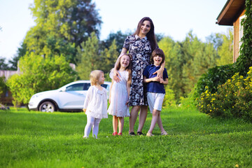 Obraz premium Young large family on a summer morning walk. Beautiful mother with children is playing in the park.