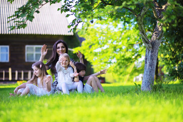 Naklejka premium Young large family on a summer morning walk. Beautiful mother with children is playing in the park.