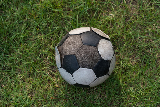 old soccer or football ball on green grass by top view