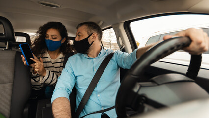 Portrait of woman in mask showing phone to taxi driver