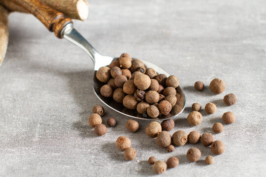 Spoon full of allspice on a gray background