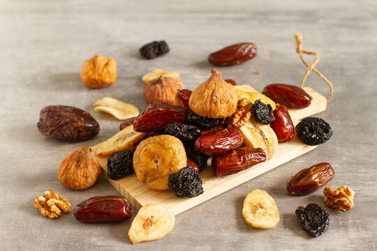 Dried fruits and berries on a wooden bowl . Raisins, nuts, cherries, plums, dried apricots, dates, pineapples, figs, bananas.