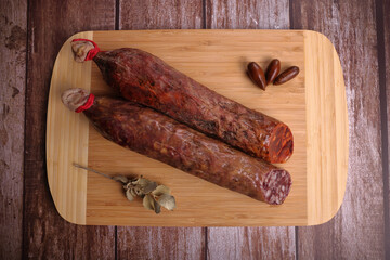 Iberian sausage and Iberian chorizo on cutting board and dark wooden table.