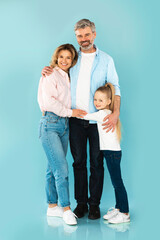 Happy Family Embracing Standing Together Posing Over Blue Studio Background
