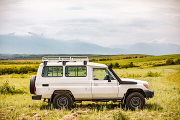 Profile of off-road vehicle parked on field in front of Accursed Mountain Range in Gjakovë, Kosovo - obrazy, fototapety, plakaty